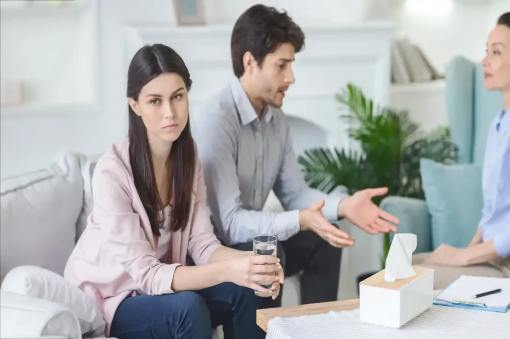 Couple looking sad while a man speaks with a lawyer, representing legal consultation.