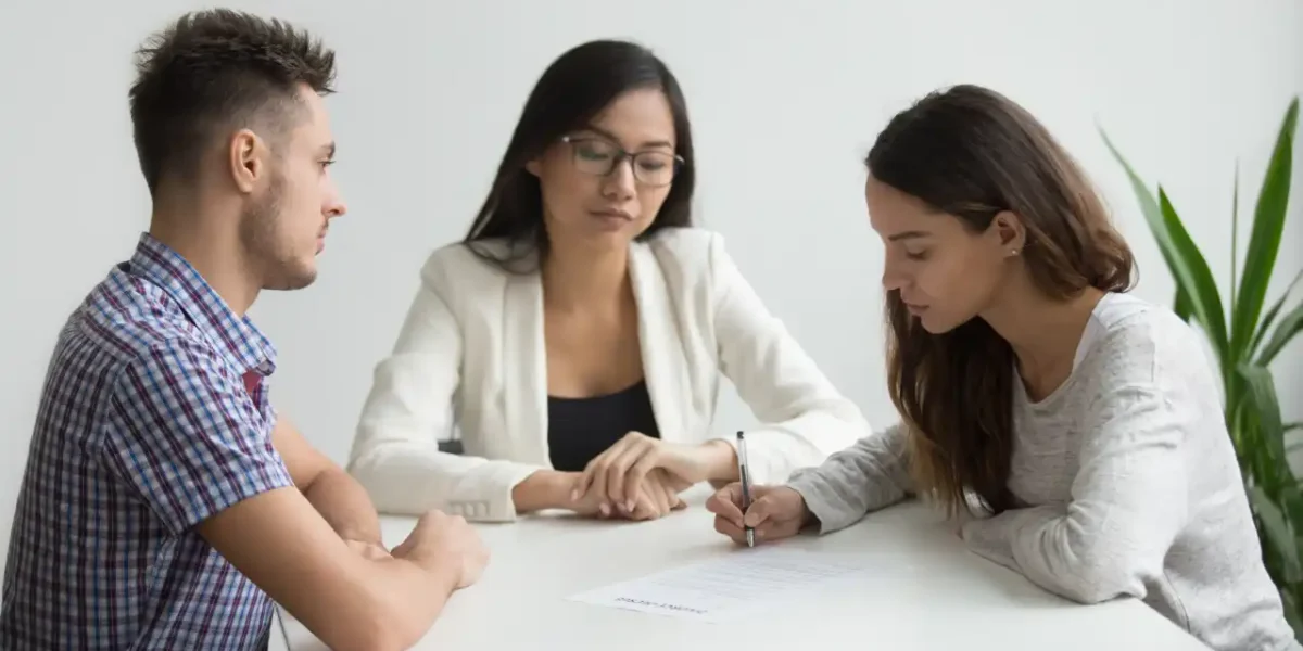 A couple signing a divorce agreement with a lawyer during a consultation.