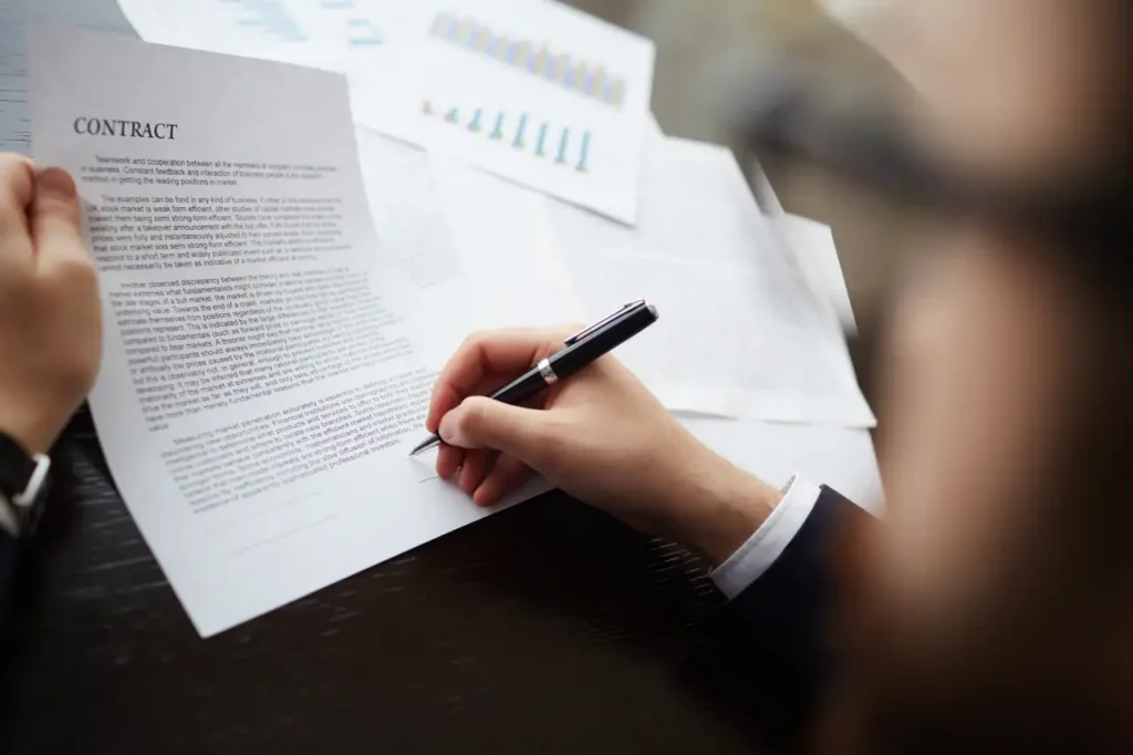 Binding Financial Agreement BFA A person signing a business contract document during a legal agreement meeting.