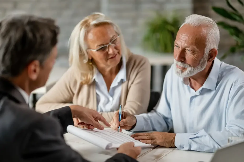 Older couple discussing and signing legal documents with a lawyer during a consultation.
