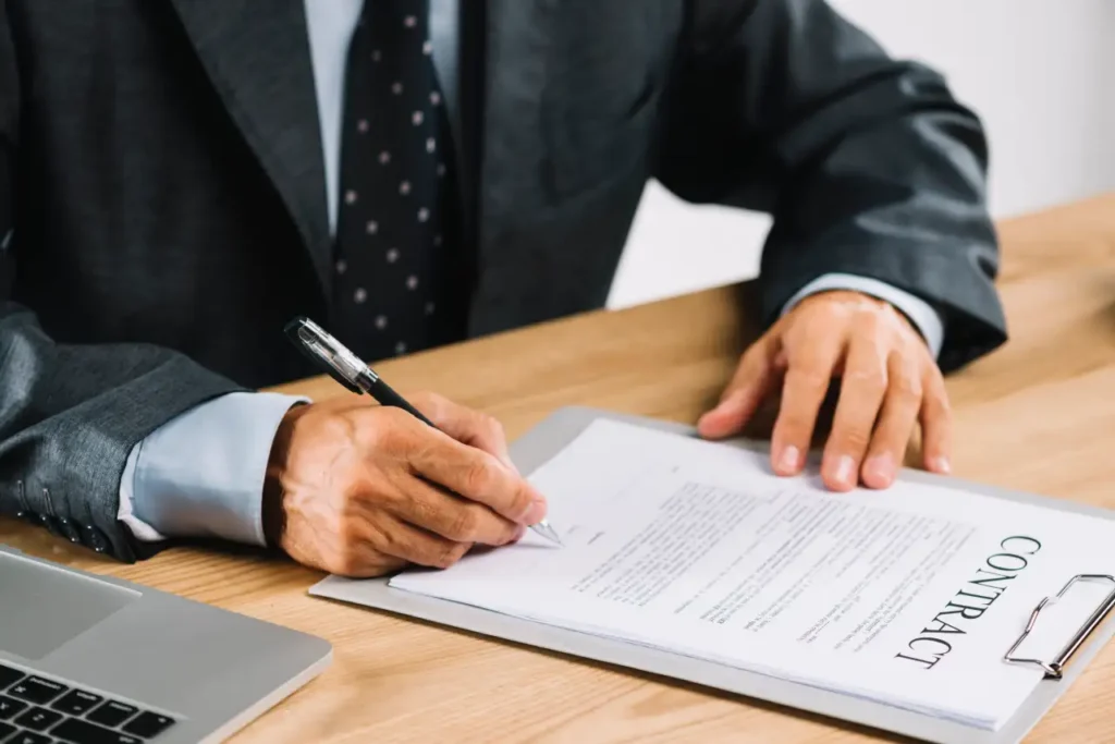 A Lawyer signing a legal contract document at an office desk.